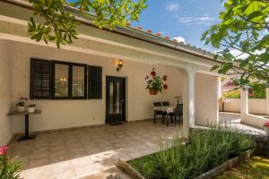 eine Terrasse eines Hauses mit einem Tisch und Stühlen in der Unterkunft Apartment Dinka in Čižići