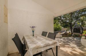 a table with chairs and a vase of flowers on it at Apartment Dinka in Čižići