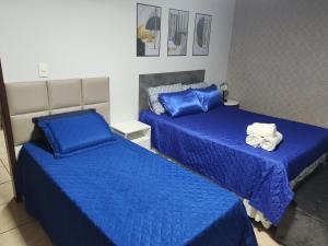two beds in a room with blue sheets and towels at Sobrado familiar Barbacena in Barbacena
