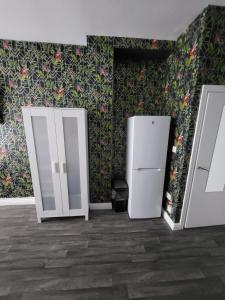 a room with two refrigerators and a wall with flowers at City Centre Studios 3 in Leicester