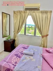 a bedroom with a purple bed with a window at Sanie Guest Room Suria A' Apartment, Bukit Merah Laketown Resort in Kampong Kubu Gajah