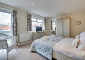 a bedroom with a bed and a tv and a window at The Haven in Southwold