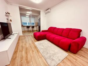 a red couch in a living room with a flat screen tv at Avangarde Apartment in Bucharest