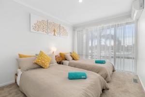 two beds in a room with a window at Absolute Waterfront Marina Views in Patterson Lakes