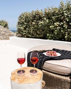 Aura Suites Paros في ناوسا: كأسين من النبيذ على طاولة مع طبق من الطعام