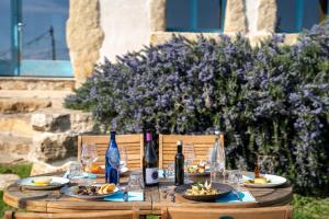 Is Perdas Rural Retreat & Spa في Gergei: طاولة خشبية مع زجاجات النبيذ وأطباق الطعام