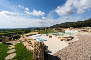 a swimming pool with a rock retaining wall next to a hill at Is Perdas Rural Retreat & Spa in Gergei