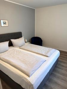 Una cama blanca grande en una habitación con una silla. en Bungalow Süüdstraat, en Norderney