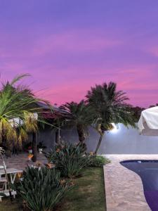 a resort with palm trees and a purple sky at Pousada Dona Emilia in Brotas