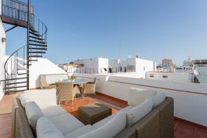 d'un balcon avec un mobilier blanc et une table sur le toit. dans l'établissement El Atico de los INGLESES by Cadiz4Rentals, à Cadix