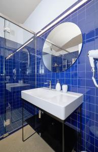 マリーナ・ディ・ラグーザにあるPetrantica Resortの青いタイル張りのバスルーム(シンク、鏡付)