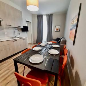 a dining room table with orange chairs and a kitchen at Casa Sobit in Turin