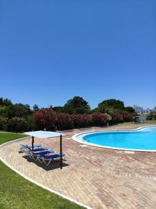 a swimming pool with two lounge chairs and a table at Prainha Clube in Alvor