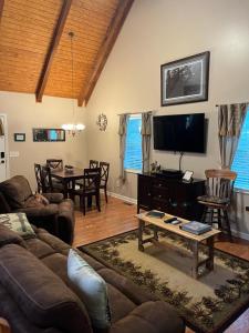 a living room with a couch and a tv at The Grindle Bridge Cabin in Dahlonega