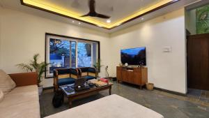a living room with a couch and a table with a laptop at Aaranya - A Boutique Stay in Bhopal