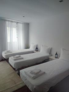 um quarto com duas camas com lençóis brancos e uma janela em Balada dos Mares Vila em Vila do Conde