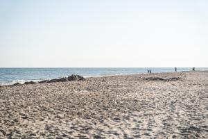 una spiaggia con persone che camminano sulla sabbia e sull'oceano di Glamping Ameland a Buren