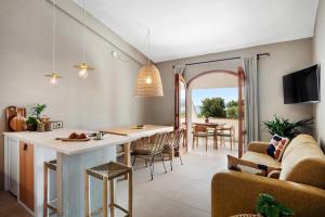 Porto Istana的住宿－Baia Dorata beach apartment，厨房以及带桌椅的起居室。