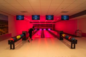 a man bowling in a bowling alley with pink lights at Glamping Ameland in Buren