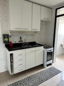 a kitchen with white cabinets and a sink and a stove at Apartamento Top Morumbi in São Paulo