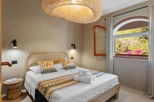 a bedroom with a bed with a window and a chandelier at Baia Dorata beach apartments in Porto Istana