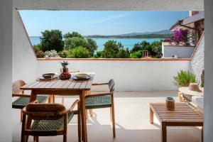 a patio with a table and chairs and a view of the water at Baia Dorata beach apartments in Porto Istana