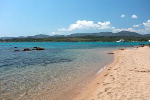 a beach with the ocean and mountains in the background at Baia Dorata beach apartments in Porto Istana