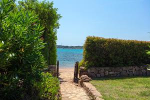 a path leading to the water with a stone fence at Baia Dorata beach apartments in Porto Istana