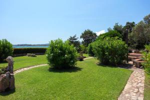 a park with grass and bushes and benches and trees at Baia Dorata beach apartments in Porto Istana