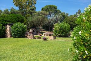 a garden with a bench and trees in the background at Baia Dorata beach apartments in Porto Istana
