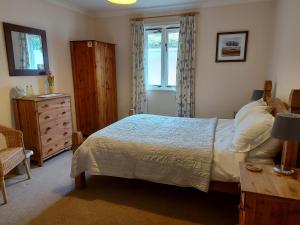 a bedroom with a bed and a dresser and a window at The Chalets in Eskdale