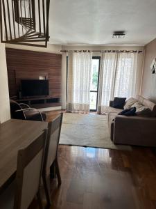 a living room with a couch and a table and a television at Apartamento Top Morumbi in São Paulo