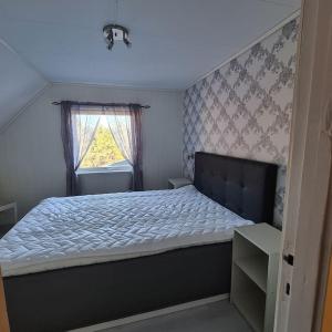 1 dormitorio con 1 cama grande y ventana en Koselig hus med hage i Herøy på Sunnmøre., 