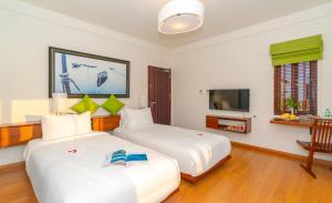 two beds in a hotel room with a tv at Elites Riverside Hotel & Spa Hoi An in Hoi An