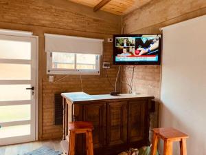 a room with a tv on a wall with a counter and stool at cabaña Palmira in Santa Rosa de Calamuchita