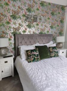 a bedroom with a bed with a floral wallpaper at Tree Fern Barn in St Austell