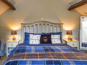 a bedroom with a blue bed with pillows at Beeswax Cottage in Dalton in Furness