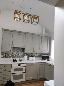 a kitchen with white cabinets and white counter tops at Tree Fern Barn in St Austell