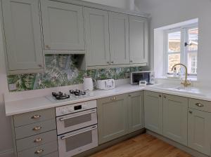 eine Küche mit weißen Schränken und einem Waschbecken in der Unterkunft Tree Fern Barn in St Austell