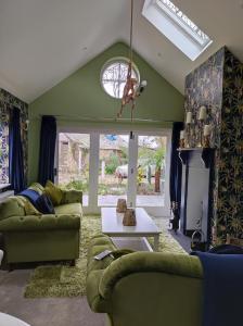 a living room with two green couches and a fireplace at Tree Fern Barn in St Austell