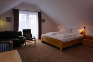 a bedroom with a bed and a chair and a window at Hotel Pension Julia in Norddeich
