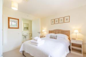 a white bedroom with a bed and a sink at Fig Cottage in Eastdean