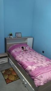 ein Bett mit einer rosa Bettdecke mit einem Hund darauf in der Unterkunft 2 minutes a l'aéroport in Marrakesch