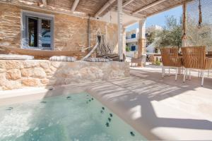 un patio con piscina, mesa y sillas en TERRA E SOLE spa suite Aegina, en Vathí