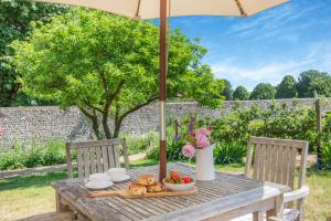a wooden table with an umbrella and a bowl of fruit at Fig Cottage in Eastdean