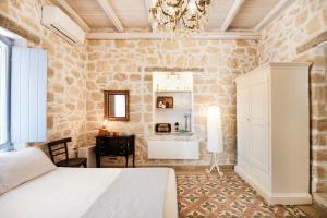 a bedroom with a bed and a desk and a chandelier at TERRA E SOLE spa suite Aegina in Vathí