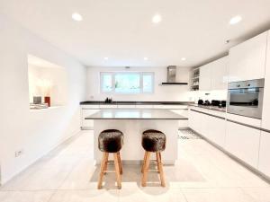 a kitchen with white cabinets and a island with two stools at • Boutique Villa 26 • in Gambarogno in Gambarogno