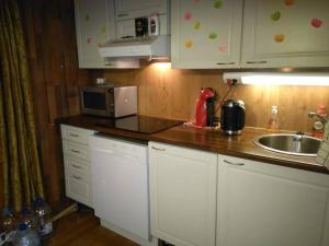 una cucina con armadi bianchi, lavandino e forno a microonde di Holiday Cabin Kerimaa 41 a Savonlinna