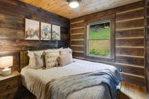 una camera da letto con pareti in legno, un letto e una finestra di Eagle Ridge Creek a Banner Elk