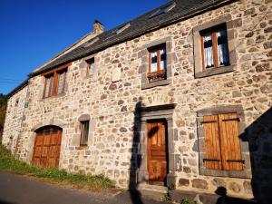 ein altes Steingebäude mit Holztüren und Fenstern in der Unterkunft Maison de Varennes in Chambon-sur-Lac